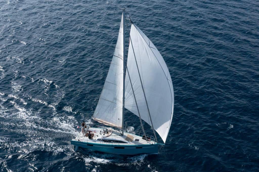 Voilier SailEazy, RM1070 qui se nomme Ty Punch et qui est basé à Marseille. Il est de profil naviguant vers la droite. Il a une grand voile blanche et un Spinaker blanc.