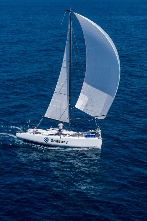 Voilier SailEazy modèleMMW33 qui ce nomme Cipango. Il est vu de profil et navigue en direction de la droite. Il a une grand voile blanche, un spinnaker blanc et une coque blanche floqué SailEazy.